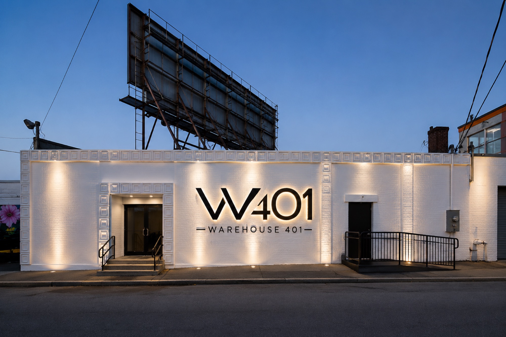 The Warehouse 401 facade at blue hour, uplit white brick under a billboard